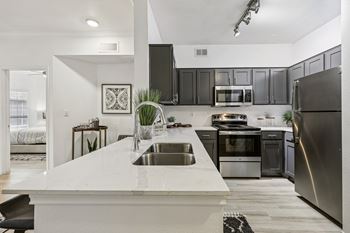 A modern kitchen with a white countertop and stainless steel appliances.